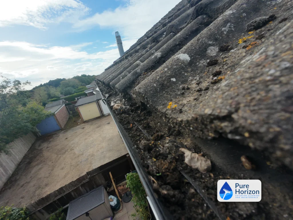 Gutter camera inspection view showing moss, leaves and compacted debris inside a roofline gutter